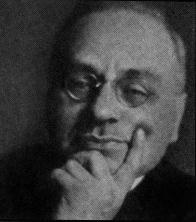 pudgy, clean-shaven little man with eyelids peaking out from horn-rimmed glasses, face resting on his hand